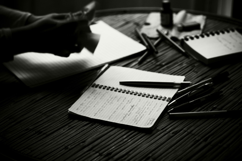 Photo noir et blanc de carnets et de stylos.