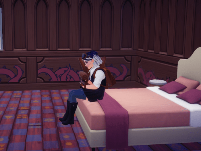 Personnage de Disney Dreamlight Valley assis dans une pièce aux tons foncés, roses et violets. Elle a les cheveux courts et bleus et est habillée d,un veston noir, un chemisier blznc et une jupe noire.